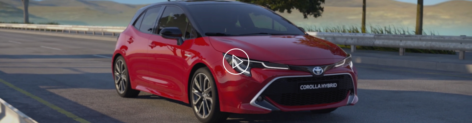 Červený vůz Toyota Corolla Hybrid jede po silnici.