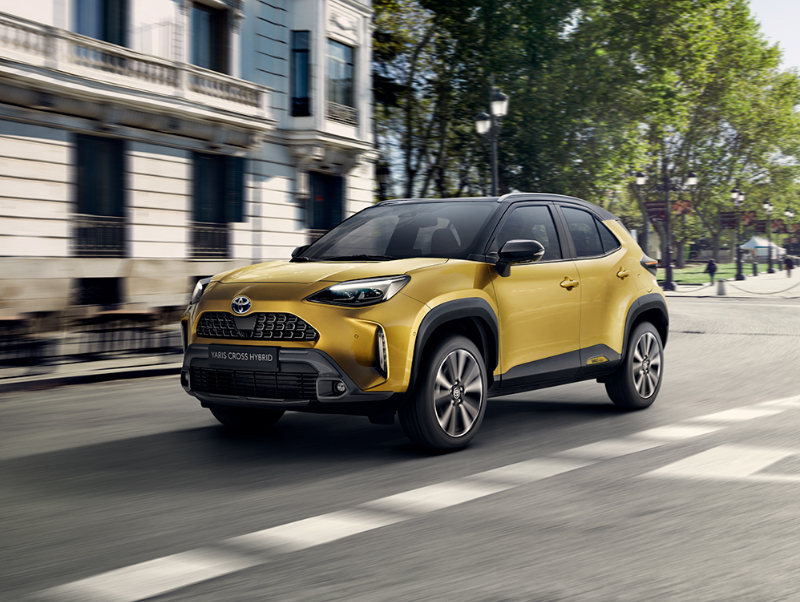 Žluté Toyota Yaris Cross Hybrid jedoucí po městské ulici.