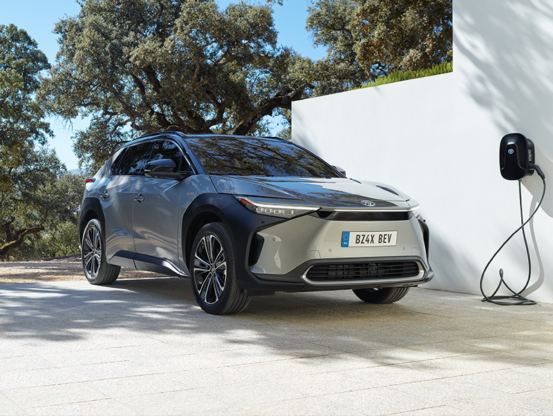Stříbrné elektrické SUV Toyota bZ4X se nabíjí u zdi.