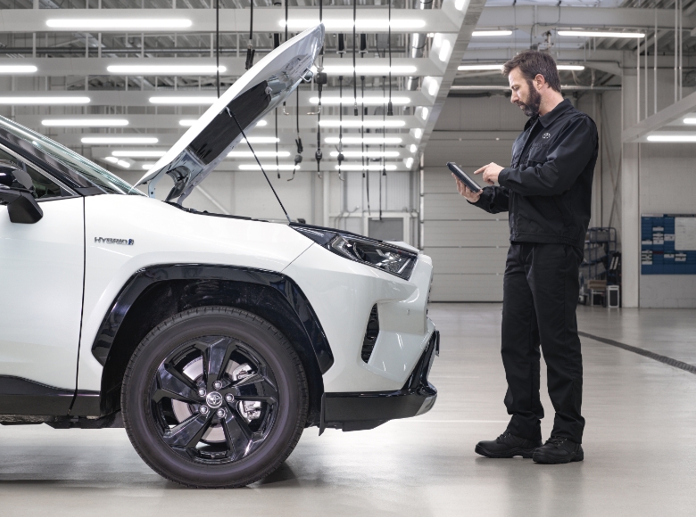 Mechanik kontroluje hybridní auto Toyotu pomocí tabletu.